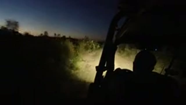 LOS CABOS MEXICO-2019: Vehicle Moves Down Dirt Path At Night With Shrubs On Either Side