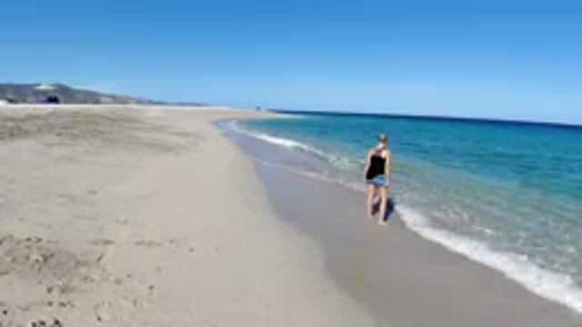 LOS CABOS MEXICO-2019: An Adult Wades With A Child On The Shore Of A Pristine Beach