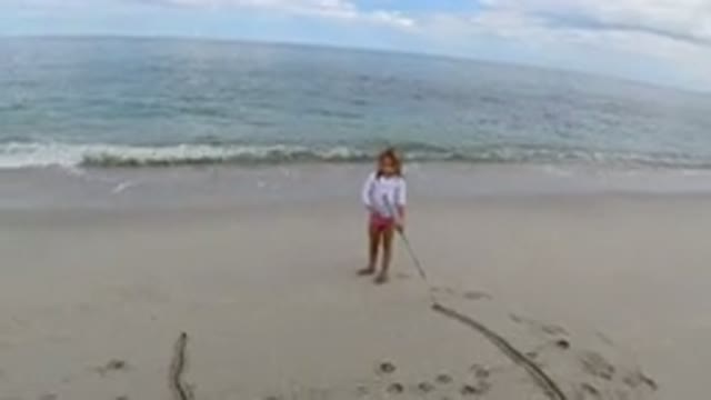 LOS CABOS MEXICO-2019: Young Girl On A Beach Drags A Stick Across The Sand