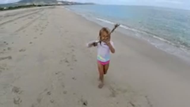 LOS CABOS MEXICO-2019: A Little Girl Waving a Stick and Posing on the Beach