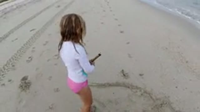 LOS CABOS MEXICO-2019: Little Girl in a Pink Swimming Suit Playing With a Stick