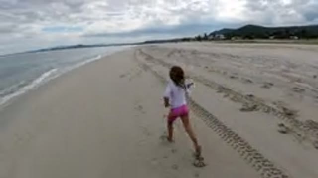 LOS CABOS MEXICO-2019: A Little Girl Running Down The Shoreline Of A Sandy Beach