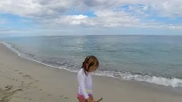 LOS CABOS MEXICO-2019: A Little Blond Girl With a Stick in Her Hand Walks Along the Beach
