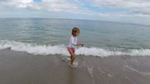 LOS CABOS MEXICO-2019: Little Girl Holding Stick Walks Away From Water