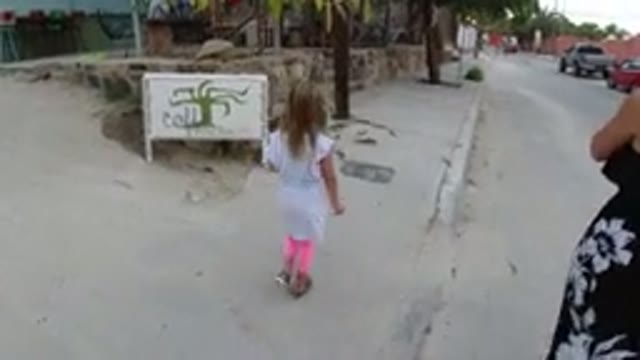 LOS CABOS MEXICO-2019: Little Girl Walks With Mom Along The Sidewalk