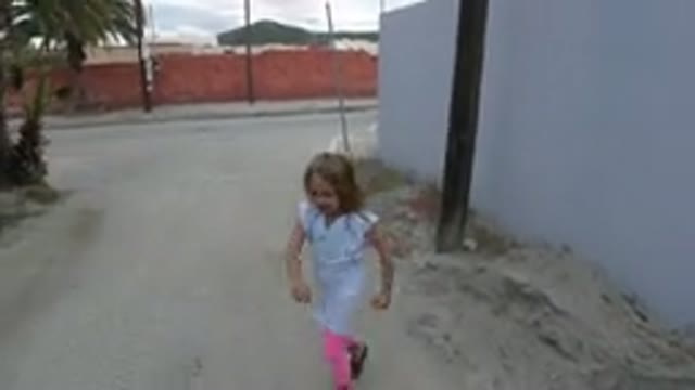 LOS CABOS MEXICO-2019: Little Girl Running In An Alley Next To A Blue Wall With