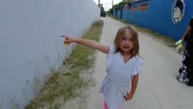 LOS CABOS MEXICO-2019: Blonde Child Pointing At White Colored Wall On Unpaved Street