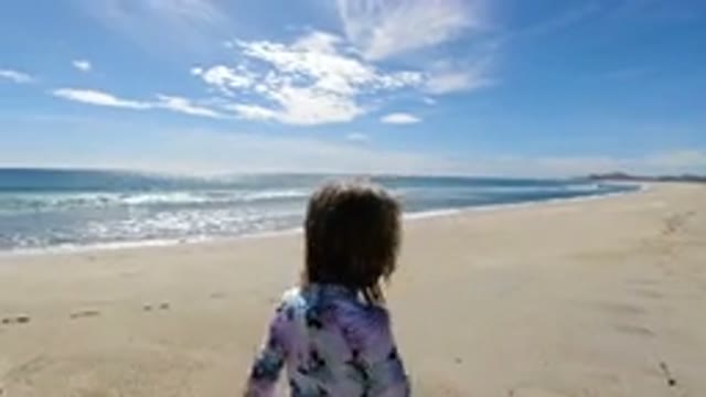 LOS CABOS MEXICO-2019: Little Girl Talking While Walking Through The Beach On A