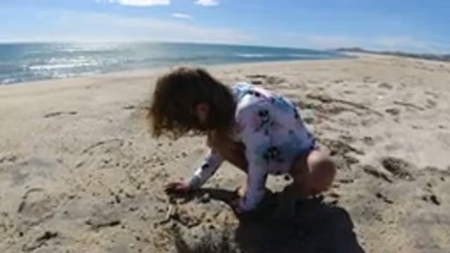 LOS CABOS MEXICO-2019: Girl Playing With Sand On A Sunny Day At The Beach