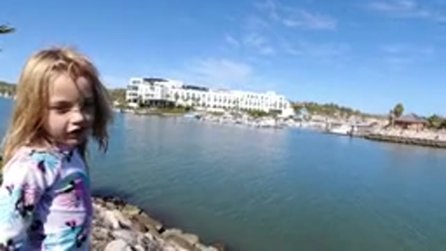 LOS CABOS MEXICO-2019: Girl Talking Enjoying Lake View with Trees and Buildings