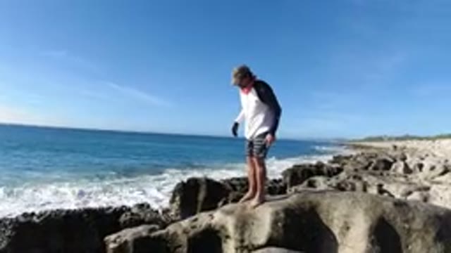 LOS CABOS MEXICO-2019: A Man On A Rock On A Beach Loses His Footing But Catches
