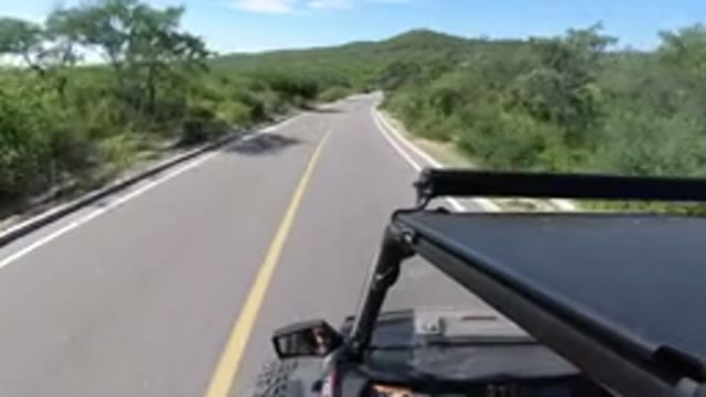 LOS CABOS MEXICO-2019: A Vehicle Travels Along A Paved Road Through Some Bushes