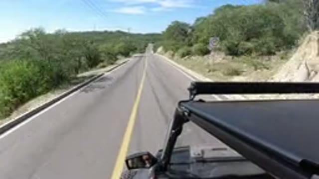 LOS CABOS MEXICO-2019: Jeep Driver Speeds Down Two Lane Road In Beautiful Scenery