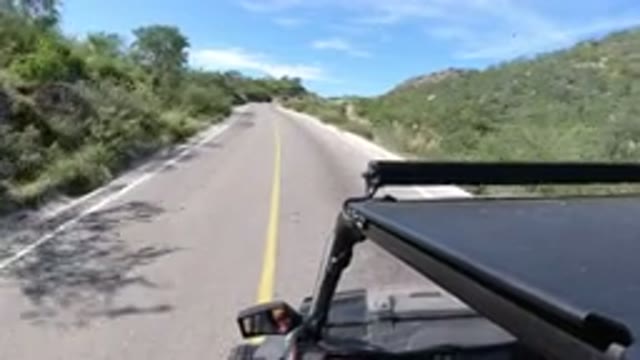 LOS CABOS MEXICO-2019: A Black Wrangler Driving Around A Bend On An Empty Highway