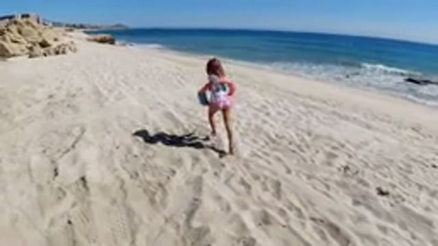 LOS CABOS MEXICO-2019: Young Girl Runs On Sandy Beach With Water To The Right