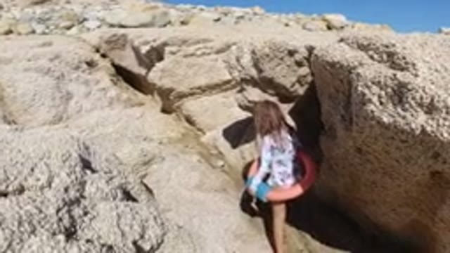 LOS CABOS MEXICO-2019: Child Holding Pink Swim Tube Exploring Rock Formations In