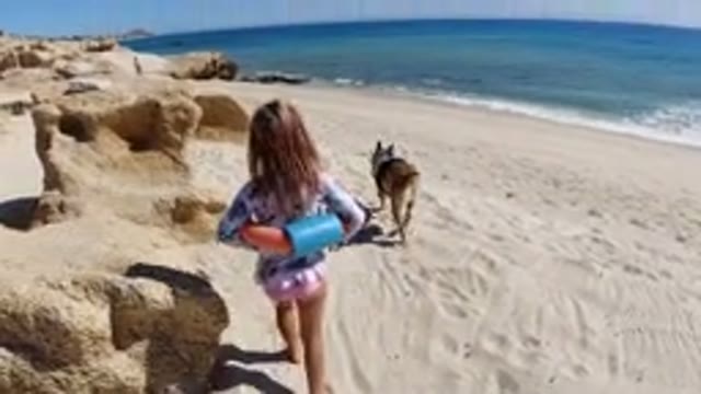 LOS CABOS MEXICO-2019: Blonde Girl in Swimsuit with Buoy Climbs Rocks on Beach