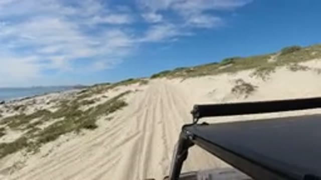 LOS CABOS MEXICO-2019: Vehicle Moves Along Dirt Path Near Body Of Water Plants