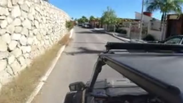 LOS CABOS MEXICO-2019: Jeep Wrangler Traveling on Road Past Trees and Houses