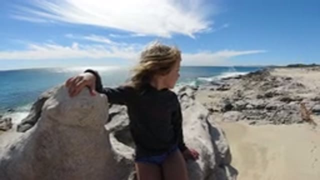 SAN JOSE DEL CABO MEXICO-2020: Young Girl Sitting On Rocks On Beach Turning And Laughing