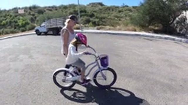SAN JOSE DEL CABO MEXICO-2020: Little Girl Trying To Ride A Bike With A Woman