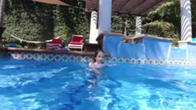 SAN JOSE DEL CABO MEXICO-2020: A Small Girl in a Blue Swimsuit Swimming in a Pool