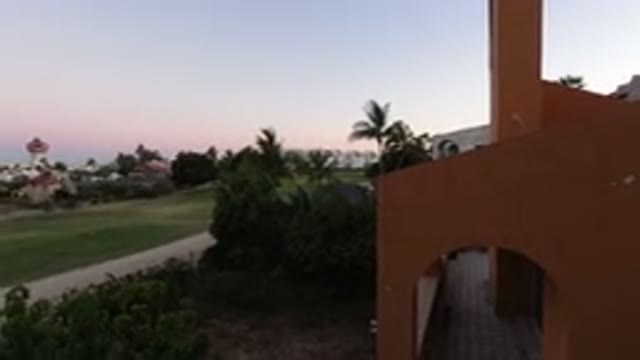 LOS CABOS MEXICO-2020: Beautiful Sunset View Of An Orange Home With Surrounding Palm Trees And Green Grass