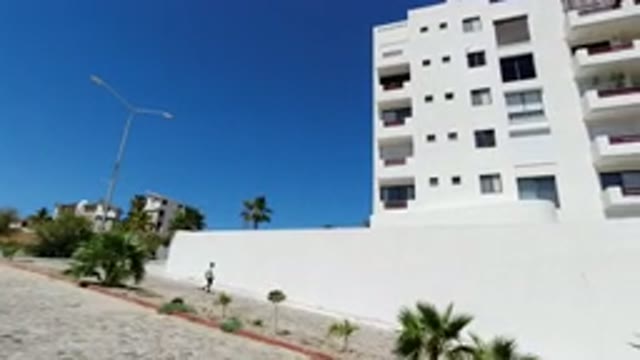 LOS CABOS MEXICO-2020: Man Walking Past White Building On Clear Hot Sunny Day