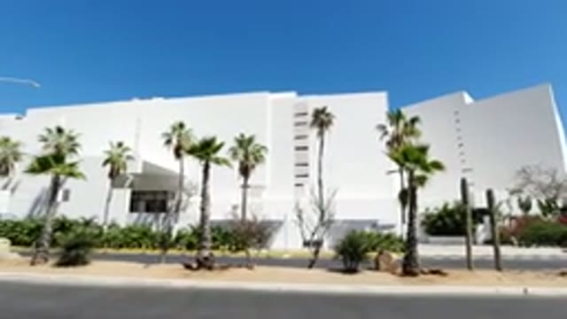LOS CABOS MEXICO-2020: Large Building With Palm Trees On The Outside And A Van Driving By