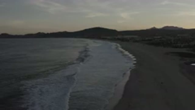LOS CABOS MEXICO-2020: A Fade View Of A Wide Beach With White Bubble Waves On It