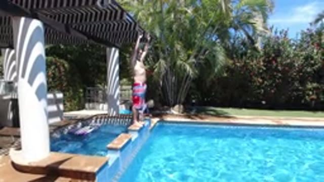LOS CABOS MEXICO-2020: Man Diving Into A Pool With A Child Nearby On A Sunny Day