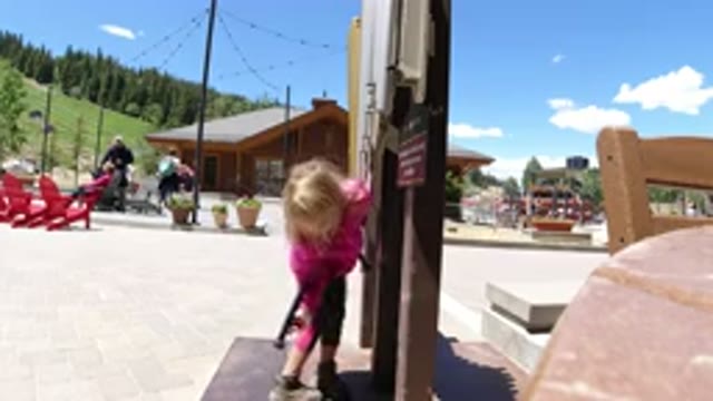 WINTER PARK COLORADO-2019: Young Girl In Pink Coat Plays Public Instrument At