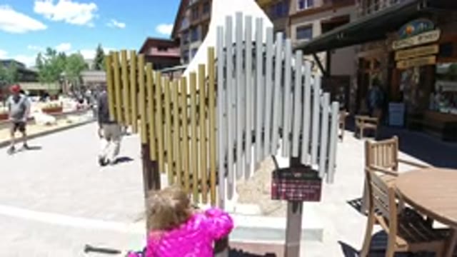 WINTER PARK COLORADO-2019: A Child Wearing A Coat Plays With Musical Pipes Along