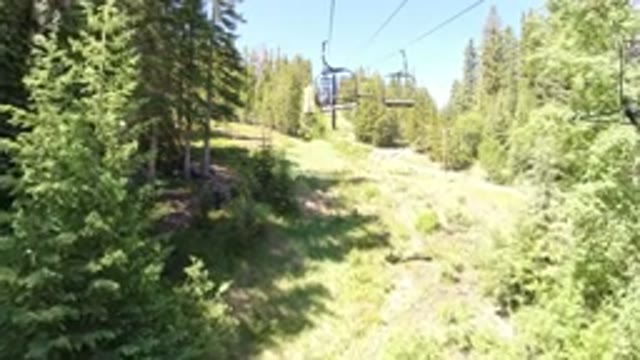 WINTER PARK COLORADO-2019: Going Up A Ski Lift In The Daytime Surrounded By Trees And Grass
