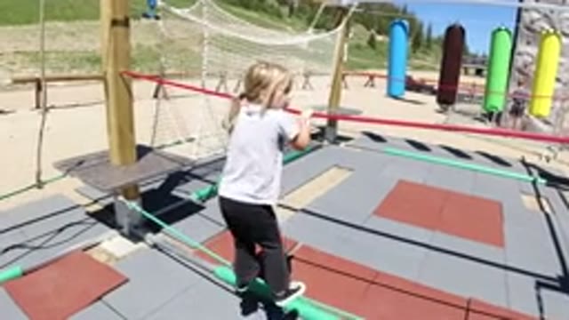 WINTER PARK COLORADO-2019: Little Girl Carefully Walks Sideways On Ropes