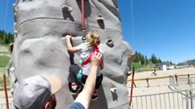 WINTER PARK COLORADO-2019: Brave Little Girl Climbing Rock Wall Supported By Dad