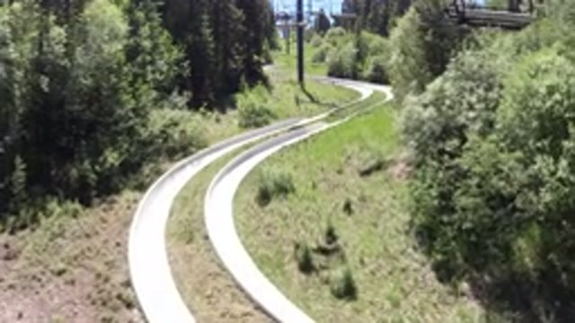 WINTER PARK COLORADO-2019: Child Slides Down Snowy Slope Near Green Trees and Logs