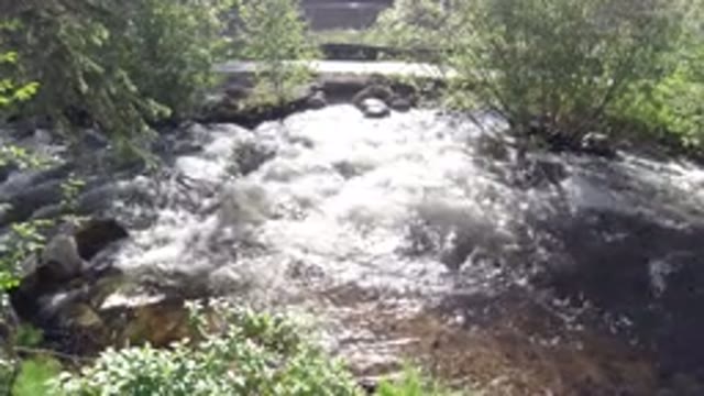 WINTER PARK COLORADO-2019: Fast River Water Rapids On Sunny Day By A Path With Trees And Bushes