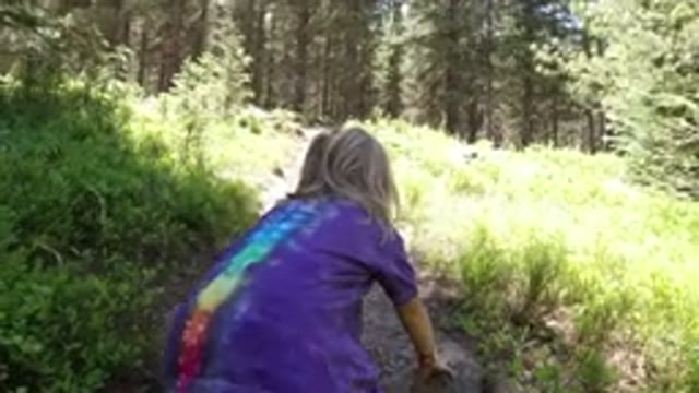WINTER PARK COLORADO-2019: Little Girl In A Purple Tie Dye Shirt And Jeans Is Crawling On A Forest Trail
