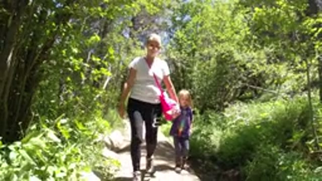WINTER PARK COLORADO-2019: Woman Hiking With Granddaughter Through A Trail In Woods