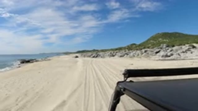 LOS CABOS MEXICO-2019: Jeep Driving Through Sand In The Beach With Mountains And