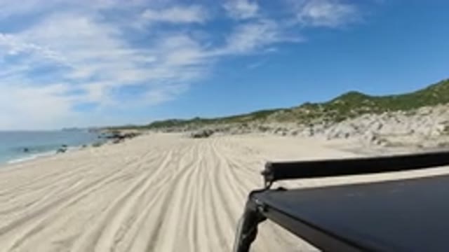 LOS CABOS MEXICO-2019: Driving Car On A Desolate Beach Slowly To Enjoy The Scenic Ocean Views