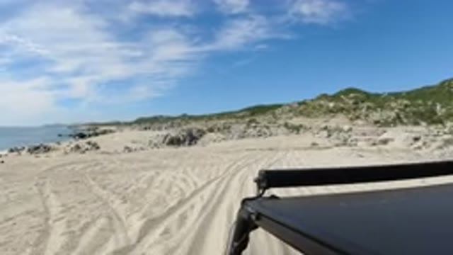 LOS CABOS MEXICO-2019: A Small Black SUV Is Riding At Moderate Speed On A Sand Road