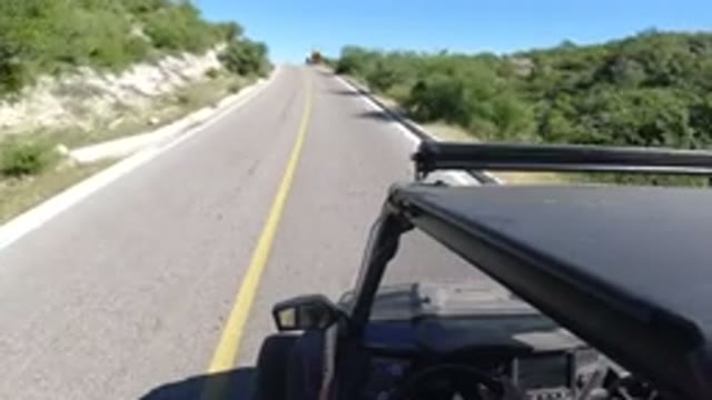 LOS CABOS MEXICO-2019: Vehicle Moving Straight on Road with Trees on Both Sides and Trucks