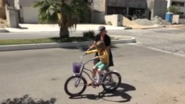 LOS CABOS MEXICO-2020: Woman Helping A Child Ride Her Bicycle In An Empty Street