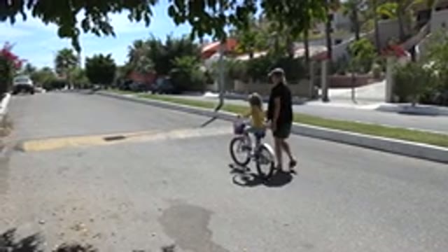 LOS CABOS MEXICO-2020: A Little Girl On Her Bicycle Supported By Her Mother On