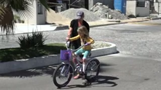 LOS CABOS MEXICO-2020: A Child With Her Parent Learning How To Ride A Bike On