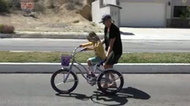 LOS CABOS MEXICO-2020: A Woman Teaching A Child To Ride A Bike In A Park During