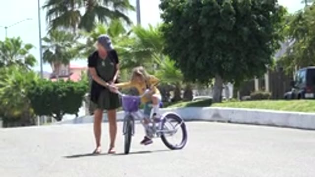 LOS CABOS MEXICO-2020: Mother In A Dark Dress Helping Her Little Daughter Ride A Bike