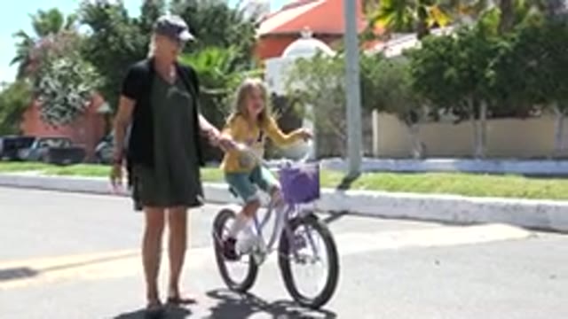 LOS CABOS MEXICO-2020: Mother Helping Her Daughter Ride A Bike By Holding Onto